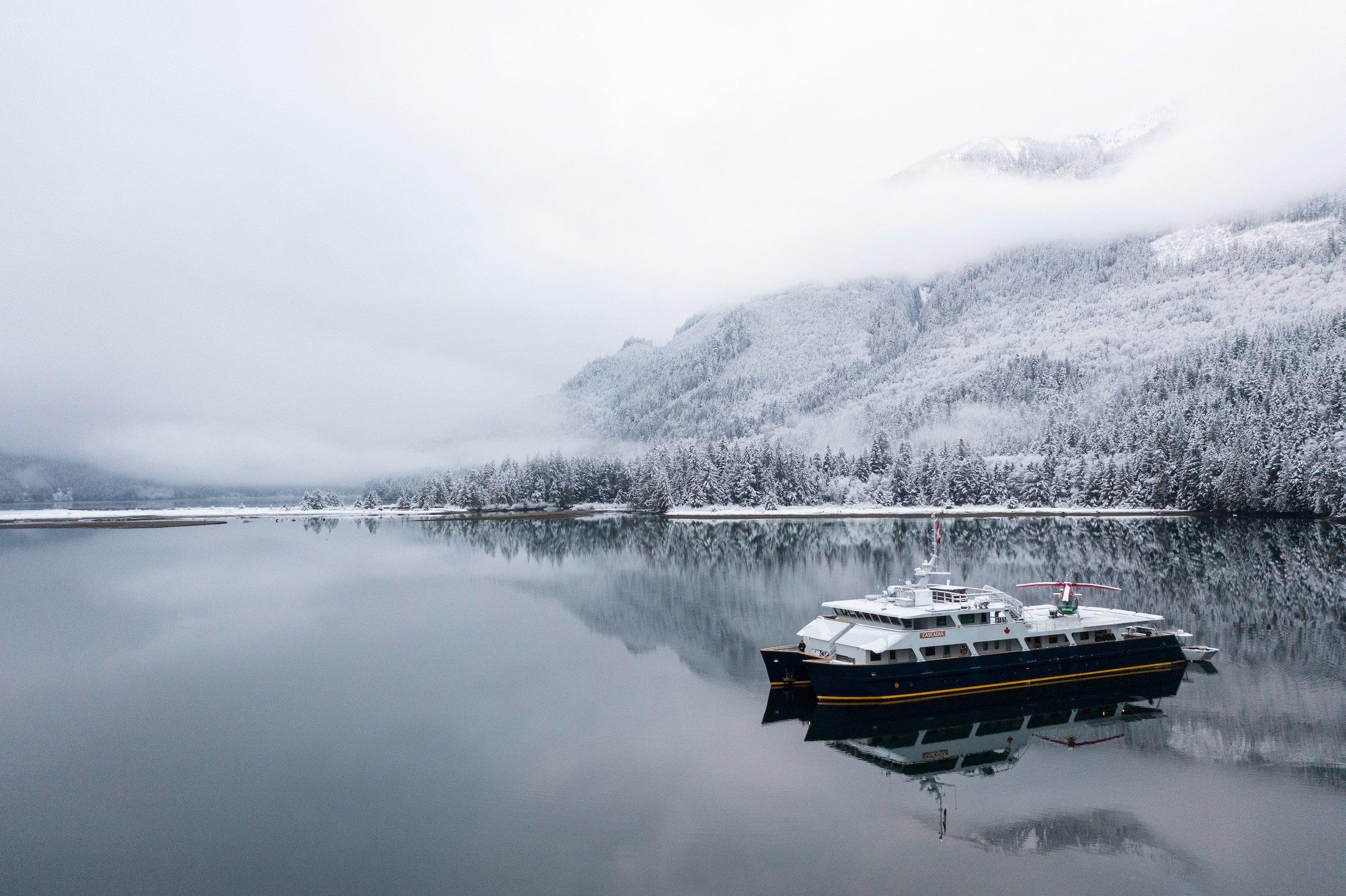 A boat floats on calm water, with a majestic mountain rising in the background.