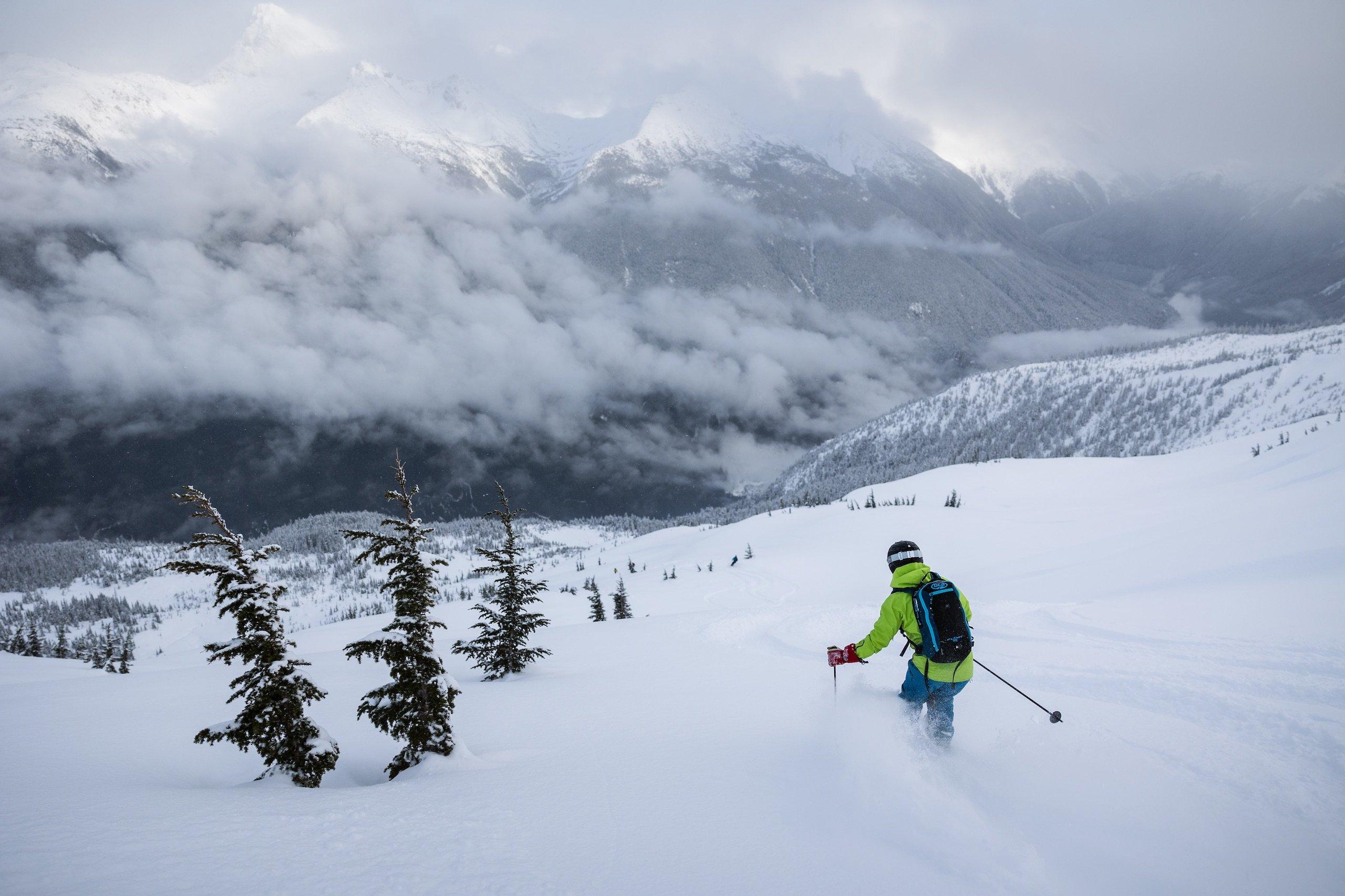 A person in a lime green jacked skiing down a snowy mountain