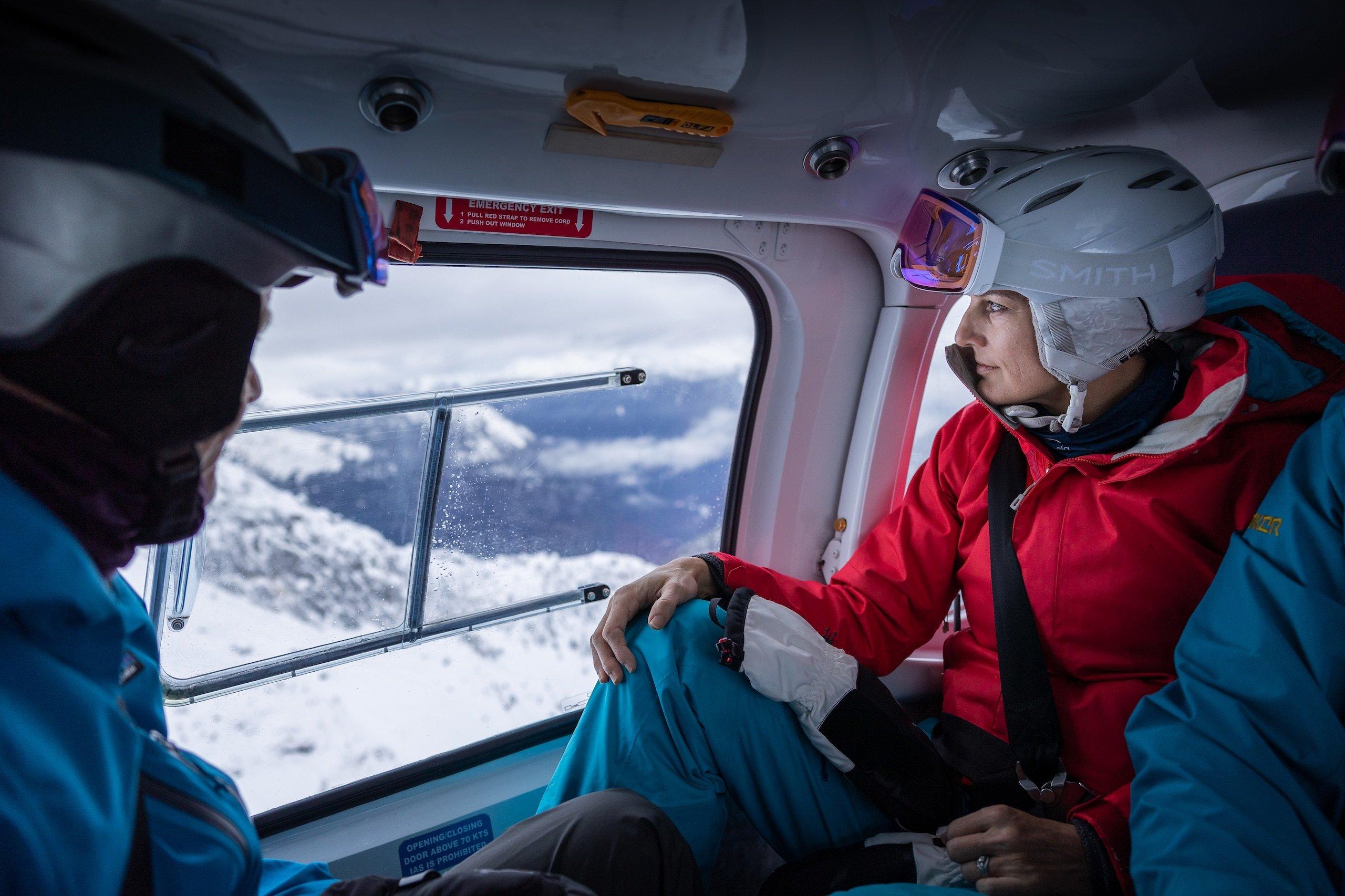 A woman looking at the mountain through the window of a helicopter