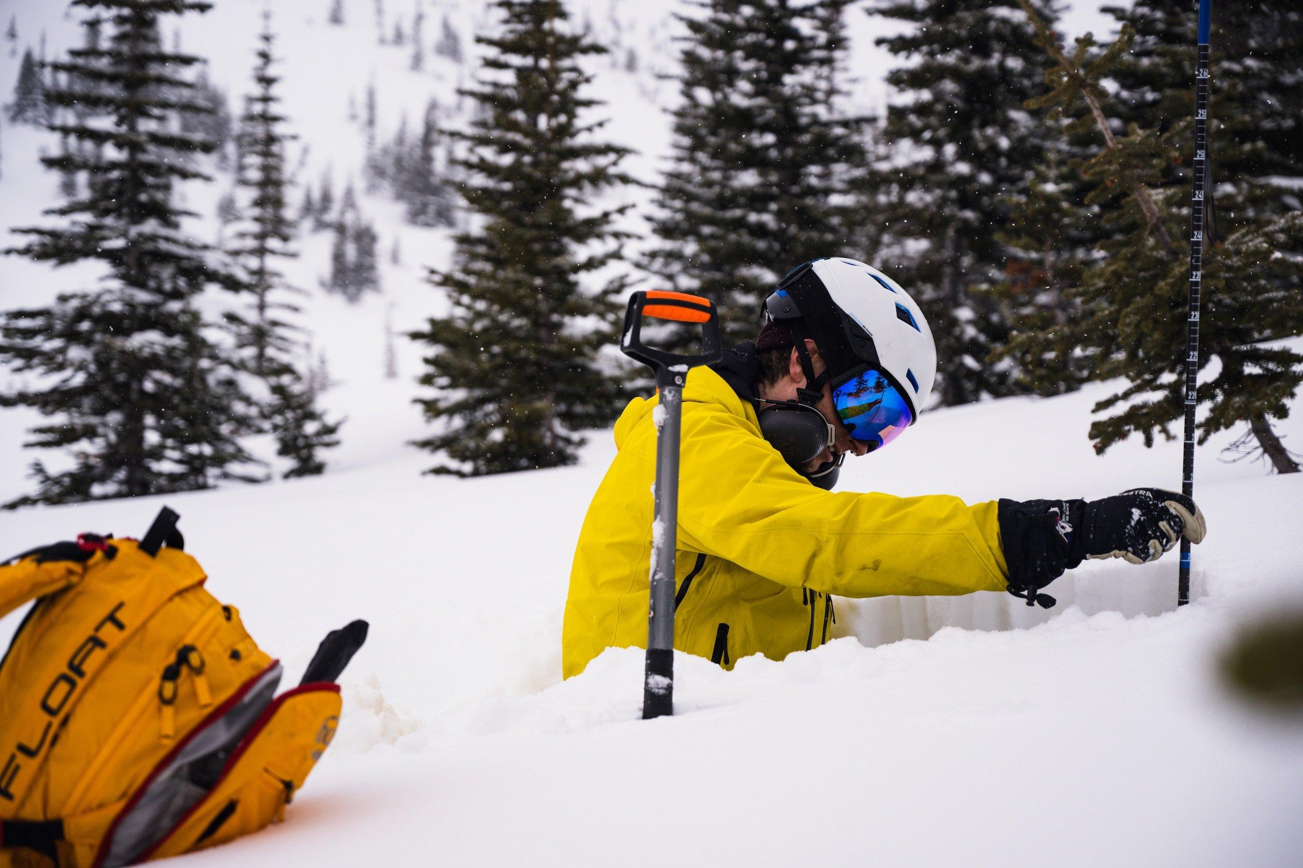 A skier measuring the height of the snow