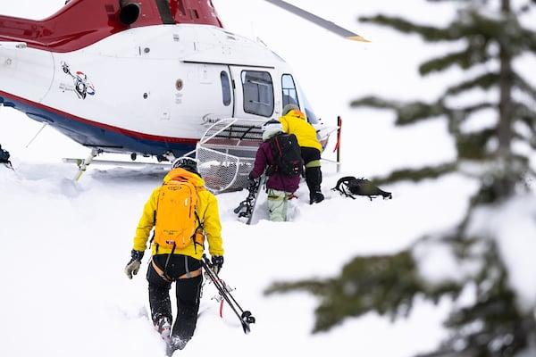 Skier walking toward a landing helicopter