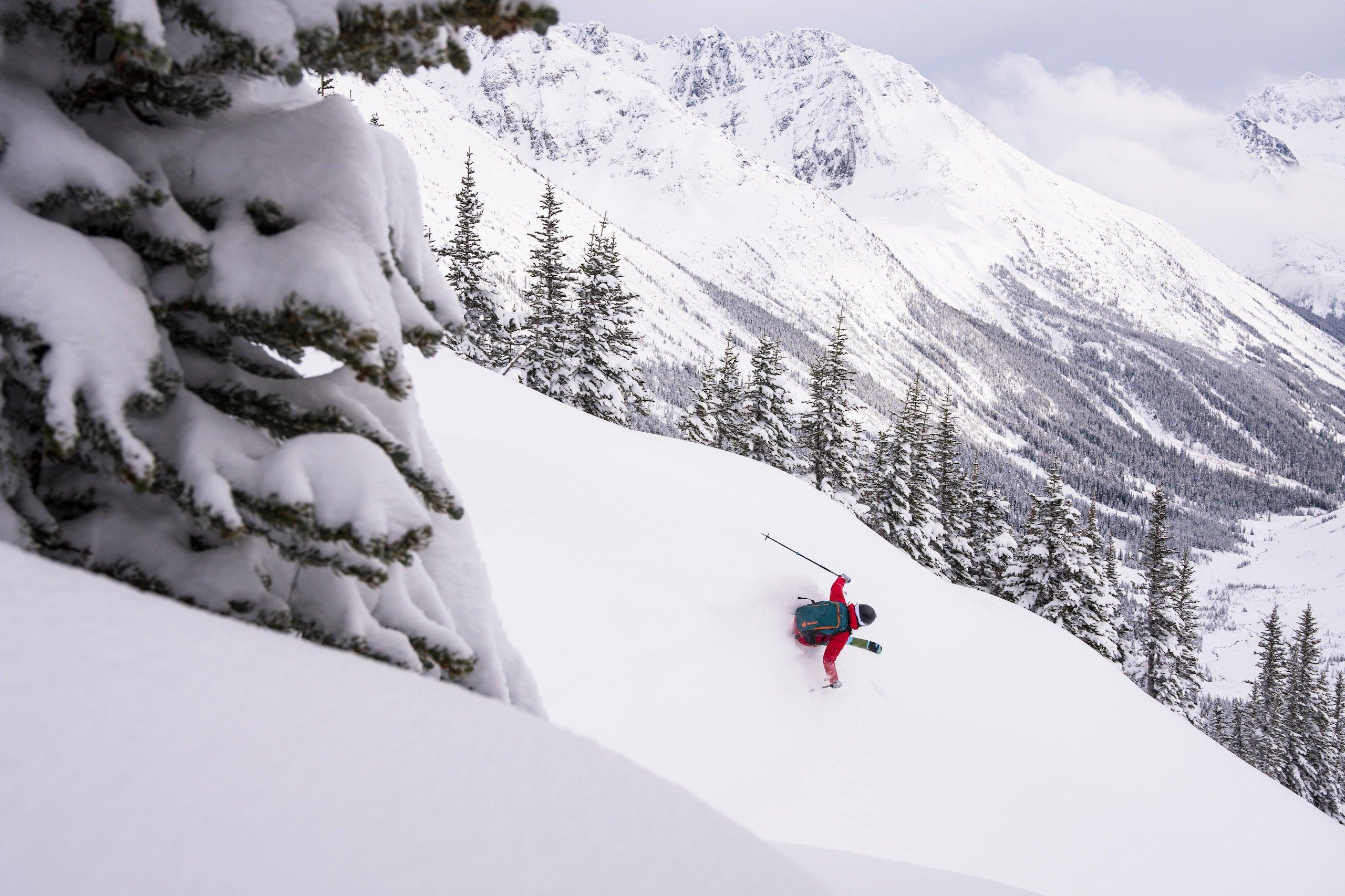 A skier in a red jacket descending a mountain