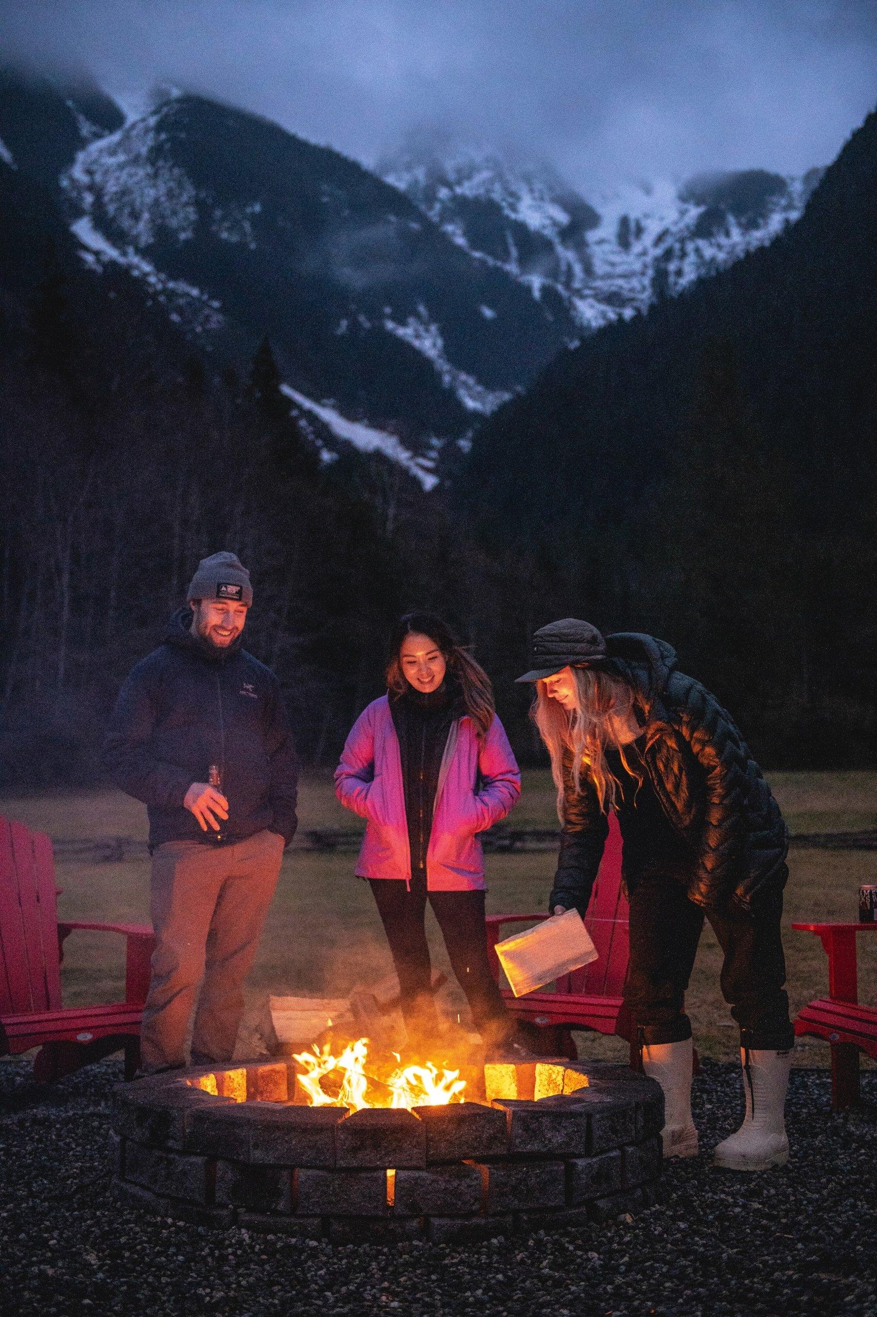 a group of friends standing around the campfire