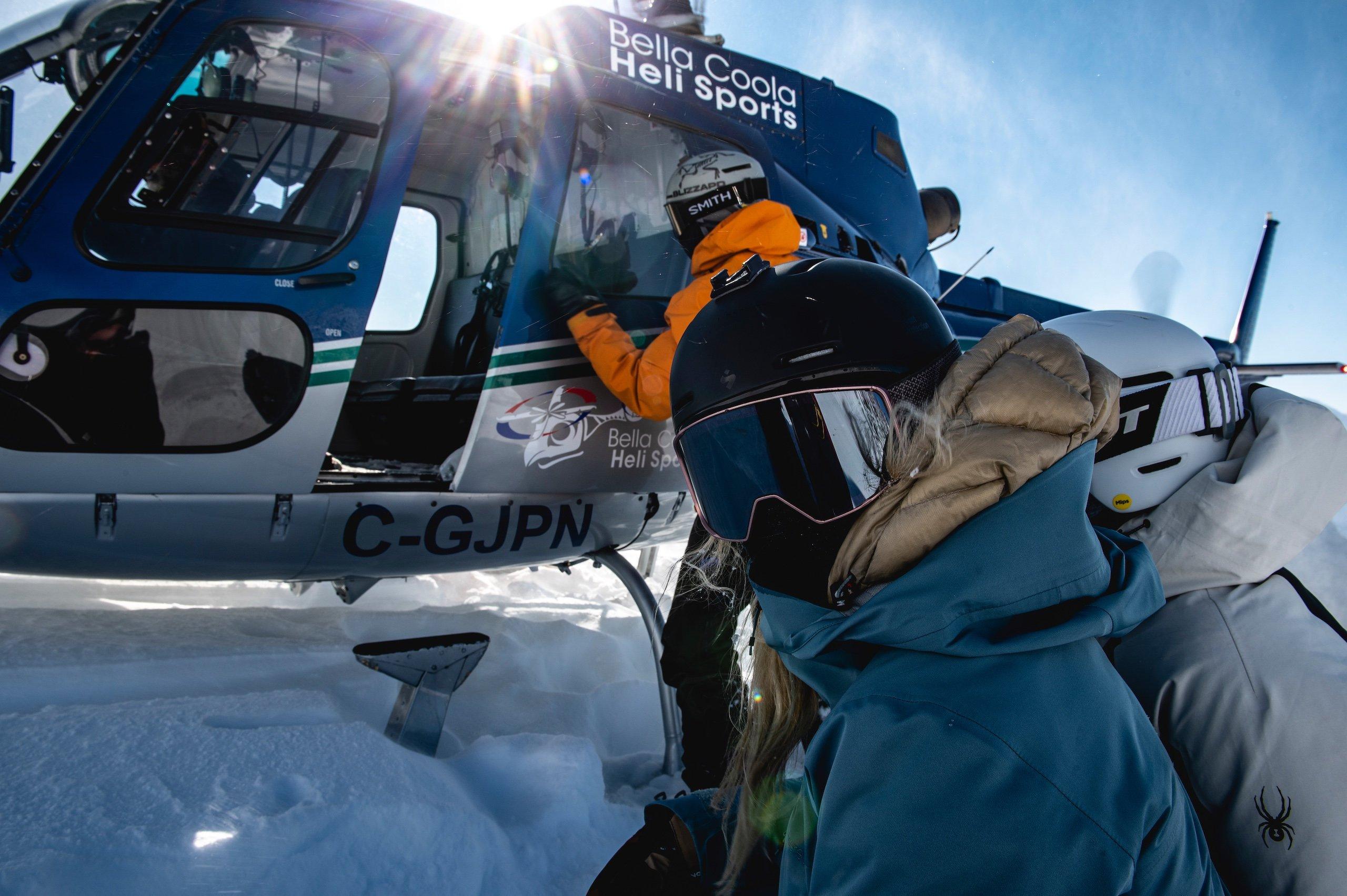 A group of skiers waiting outside of a helicopter