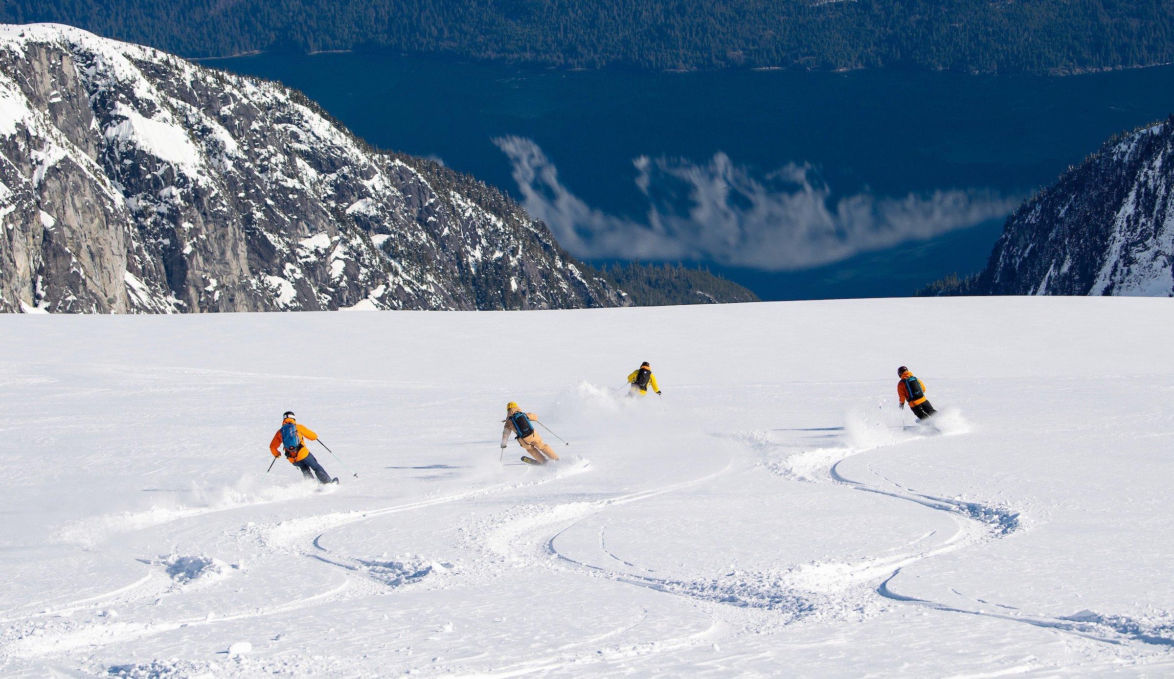 a group of four skiers descending down a mountain