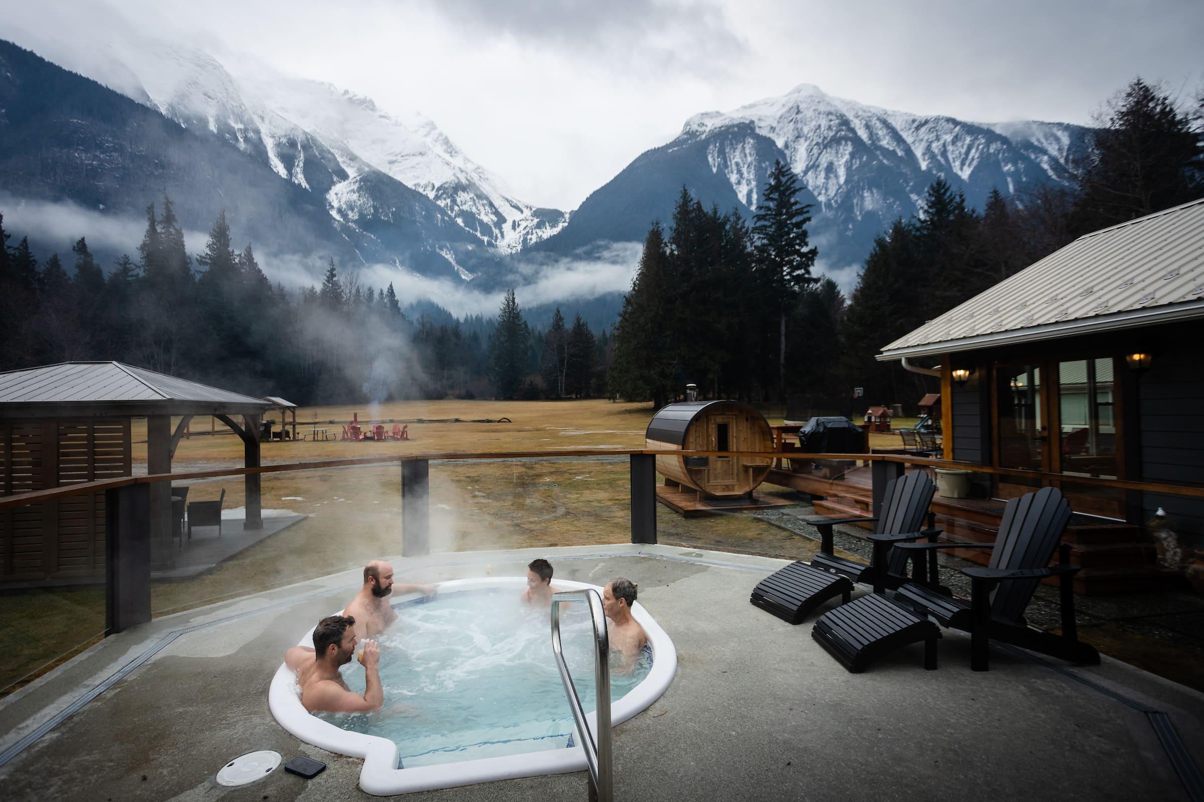 four men in a hot tub overlooking views of the mountain