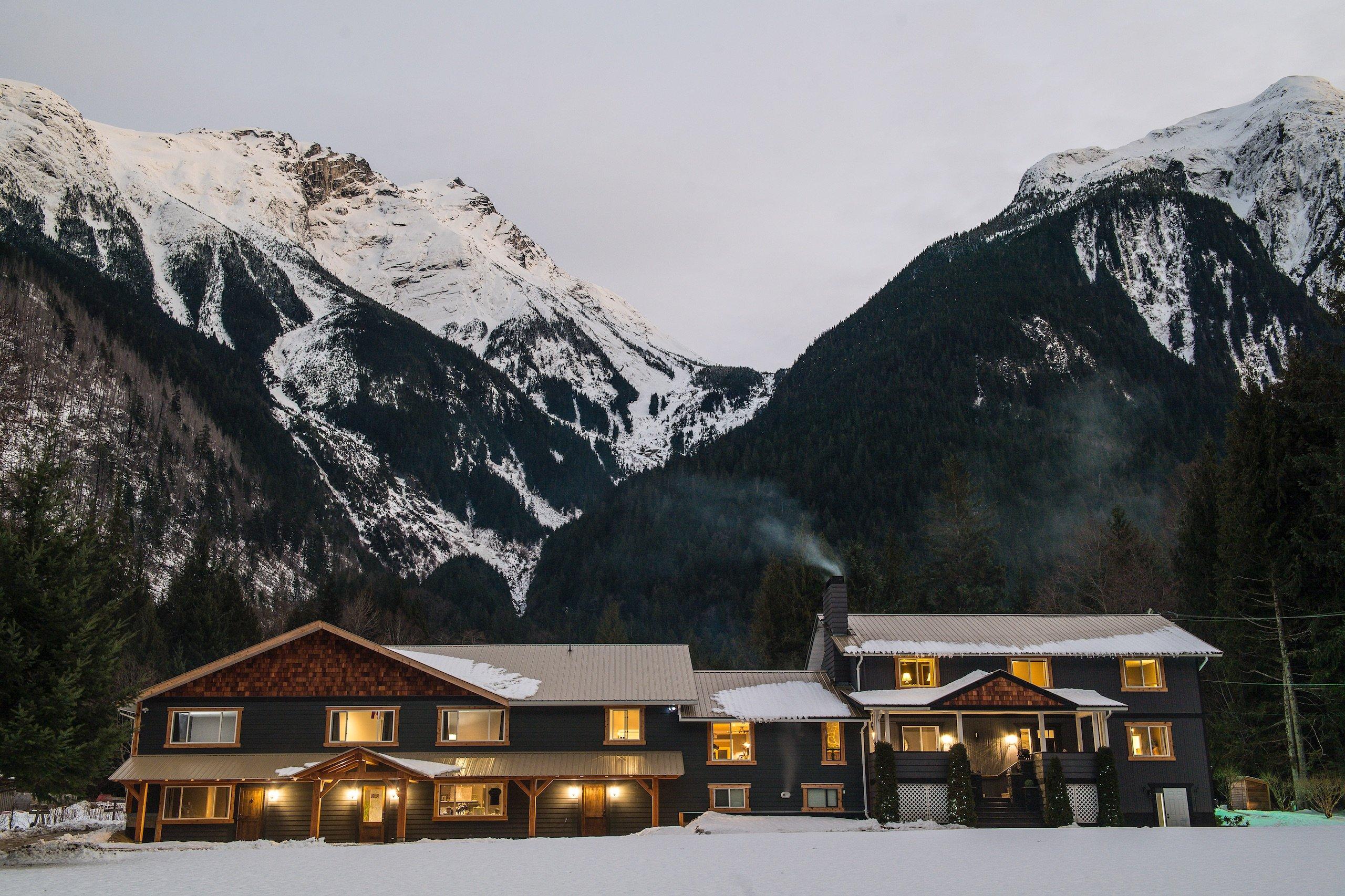 A ski lodge with mountains in the background and snow on the ground
